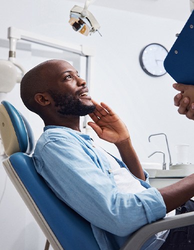 Smiling patient talking to dentist holding clipboard