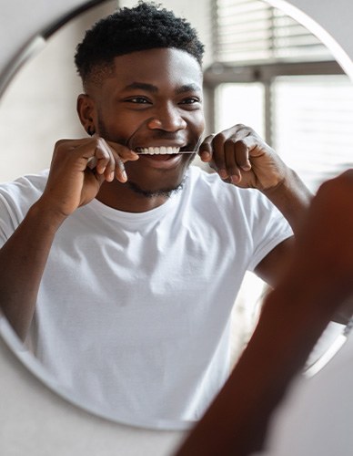 Man smiling while flossing his teeth