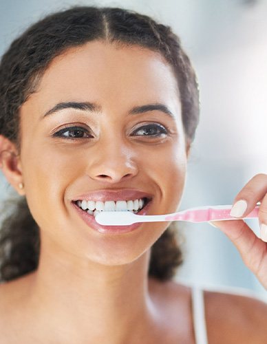 Closeup of woman smiling while brushing her teeth