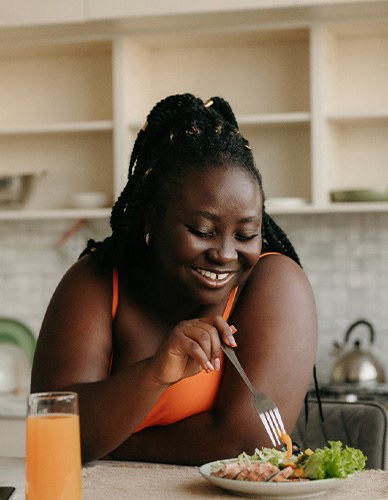 Woman smiling while eating in kitchen