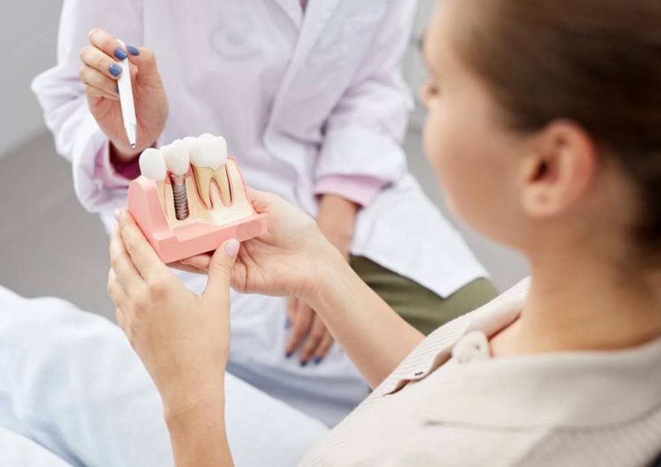 a patient holding a model of a dental implant