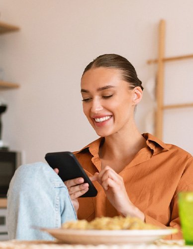 Woman smiling while looking at phone at home