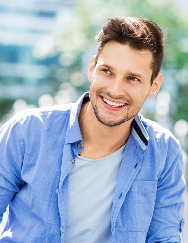 Smiling young man in an open blue button down shirt over a gray T shirt