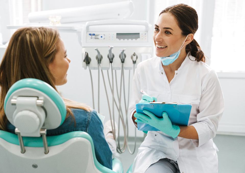 Female dentist smiling at patient while taking notes