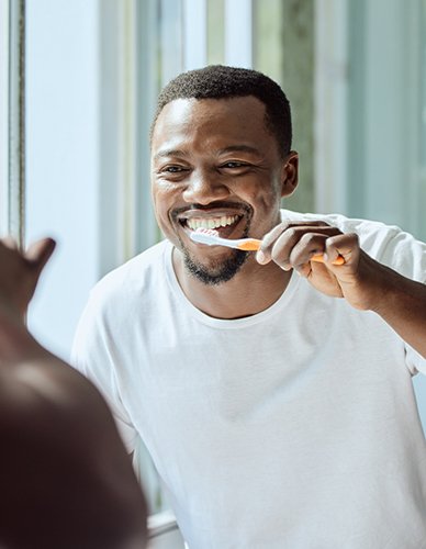 Man smiling while brushing his teeth