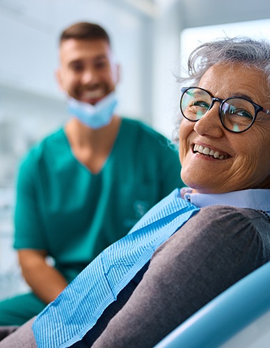 Woman with glasses smiling in treatment chair