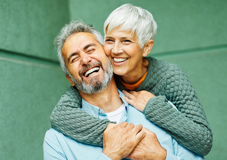 Senior couple laughing with implant dentures in Richardson, TX
