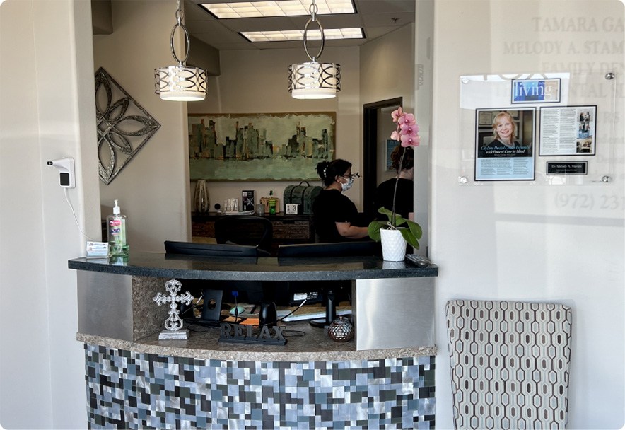 Dental team member sitting behind the front desk on a computer