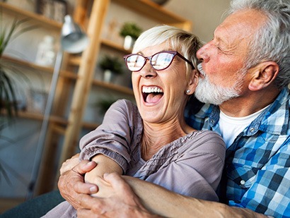 Senior man kissing his wife on the cheek after receiving dental services in Richardson