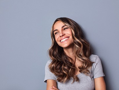 Woman with wavy blonde hair smiling and looking off to the side