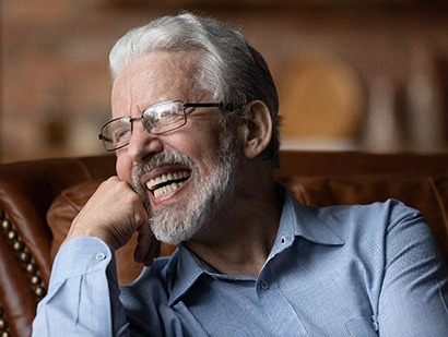 Smiling man with gray hair and a pale blue collared shirt