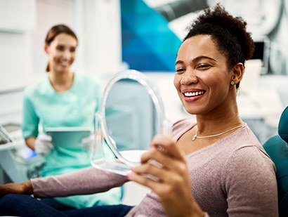 Woman in the dental chair looking at her smile in a mirror