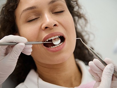 Woman closing her eyes while receiving a dental exam