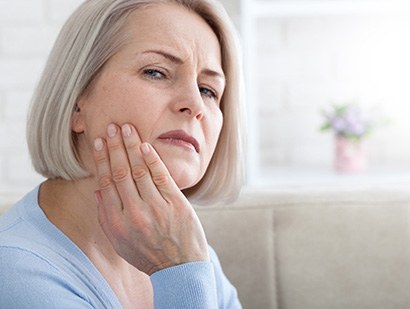 Woman wincing in pain while holding the side of her face