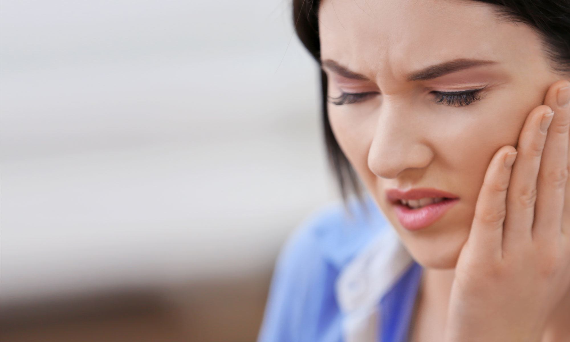 Woman experiencing pain from teeth grinding before nightguard treatment