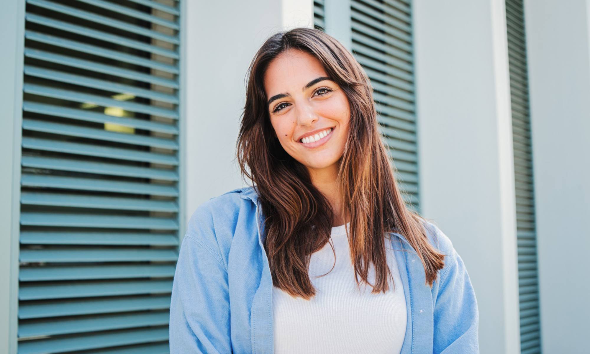 Young woman with bright teeth standing outside