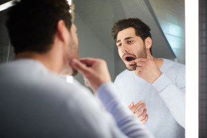 Concerned man checking his teeth in a mirror