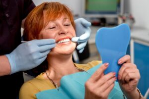 Patient looking into mirror smiling in dentist's chair.
