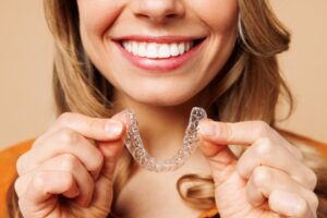 Woman smiling, holding Invisalign clear aligners